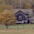 Pixelated static image of a dark house with light windows and door on a grassy field under a muted sky.