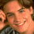 Pixelated image of a smiling person with brown hair on the left, next to stylized text and star symbols in orange and pink against black background.