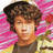 Pixelated portrait of a person with curly brown hair against pink floral background, wearing dark shirt.