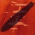 A dark, elongated object with a smooth surface rests diagonally on an orange-red pixelated background.