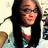 Pixelated static image of a person with long dark hair wearing a white shirt and dark jacket, holding an object in the right hand.