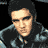 Pixelated static image of a person with dark hair and sunglasses wearing a black jacket over a light shirt against a solid black background.