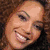 A four- shows a woman with curly brown hair in different poses: smiling, wearing a white cap, and posing with hands near her head
