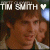Animated contact sheet showing two frames of a buddy icon with text "TIM SMITH" and heart symbols above a person's face, displayed in pixelated style on gray background.