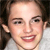 Pixelated close-up of a person with light skin, dark eyes, and brown hair tied back, wearing a light-colored top with a visible collar.