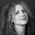 Black-and-white pixelated portrait of a person with curly hair, neutral expression, and visible neck against dark background