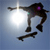 Pixelated static icon of a dark-colored figure performing a skateboarding trick against a light blue gradient background with a bright white sunburst effect.