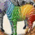A zebra with rainbow-colored stripes stands on a gray background, with text below reading 'Dare to be different' in purple letters.