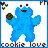 Pixelated blue character with rounded limbs, two red eyes on top of head, holding a dark green object in right hand, standing against light background.