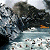 Pixelated static image shows dark rocky terrain with a small orange object on the right side, set against a light blue and white background.