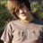 A person in a light gray t-shirt lies on green grass, with a pixelated purple and black graphic on the right side of the frame.