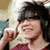 A person with dark hair and a maroon top appears in two side-by-side , each showing the same pose with one hand near their face. Below are red text elements: 'IS' on the left and 'SMART' on the right