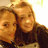 Two people with light brown hair appear in a close-up, pixelated image with warm tones and a blurred background.