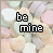 Pixelated text 'be mine' appears in black or pink over a background of pastel heart-shaped candies.