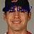 Pixelated close-up of a person wearing a dark cap with red and white details, blue text overlay across the eyes, and a red-collared shirt against a gray background.