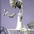 Pixelated image of a white and gray structure with curved elements against a purple background, featuring a tall central column and smaller side components.
