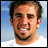 Pixelated image of a person with short brown hair and a goatee, wearing a white shirt against a blue background, next to text on pink and gray