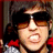 Pixelated image of a person with dark hair wearing sunglasses and red clothing, surrounded by blue text on black background.