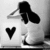 Black-and-white pixelated image of a figure with long hair holding head, next to solid black heart symbol on light background.