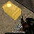 A pixelated golden cylindrical object with a bright light on top rests on a textured surface with dark and light brown tones.