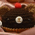 A pixelated image of a dark brown object with a red top and a circular white-and-yellow emblem, next to the word 'bitch' in white pixelated text on black.