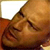 A pixelated close-up of a person's face with closed eyes, resting on a brown surface under warm lighting.