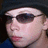 A static image shows a person wearing dark sunglasses and a black beanie against a solid green background with pixelated text.