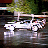 Pixelated static image of a white vehicle on water with green foliage background, likely from an old AOL buddy icon set.
