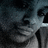Pixelated grayscale image with dark background and light foreground elements, showing abstract shapes including a curved form on the left and vertical lines on the right.
