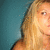 A blonde woman with shoulder-length hair appears in a static image against a teal background, her face partially cropped on the right side.