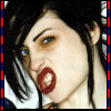 A person with dark hair and blue eyes has red lips, visible teeth, and a slightly open mouth in a close-up view.