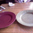 Pixelated image showing two rounded shapes, one deep purple and one light gray, positioned side-by-side on a brown surface with blurred background elements.