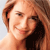 Pixelated close-up of a person with light brown hair, wearing a dark top, against a light blue background.