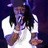 Pixelated image of a person with long dark hair wearing white clothing and holding a microphone, set against a dark purple background.