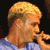 Pixelated static image of a person with blonde hair and light skin wearing a blue shirt, viewed from the side against a dark background.