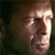 Pixelated close-up of a human face with light skin tone, dark hair, and a neutral expression against a dark background.