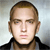 Pixelated static image of a person with short brown hair wearing a dark collared shirt against a light gray background.
