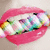 Pixelated image of a mouth with pink lips holding a colorful, abstract, multicolored object with green, blue, purple, and white sections.