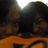 Two figures in dark clothing stand against a bright background with orange and brown tones, their faces partially obscured by pixelation.