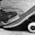 Black-and-white pixelated icon depicting a skateboard with visible wheels and deck, angled diagonally across the frame against a light background.