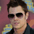 Pixelated image of a person with dark hair and sunglasses on the left, next to blue text reading "Johnny Knoxville" on a purple background.