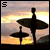 A 4-frame animated contact sheet showing a surfer silhouette with surfboards against a sunset sky, where the text "SURF" progressively appears in the top-left corner across frames.
