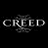 Static pixelated icon displaying the word 'CREED' in large blocky letters with a faint, blurry floral or abstract design behind it on a black background.