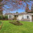 Pixelated static image of a house with white walls and dark windows on green grass under blue sky.