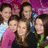 Six people pose closely together in a group photo with varied clothing colors against a purple background.