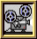 Pixelated film projector with two reels, blue and black spools, red indicator light, framed in gold border on gray background.