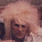 Static pixelated image of a person with light-colored hair and dark clothing against a muted background.