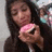 A pixelated image shows a person with long dark hair holding a pink and white object against a blurred background.