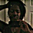 Pixelated static image of a person with dark hair and light skin, wearing a dark top with a light-colored collar, set against a blurred background with vertical elements.