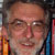 Pixelated close-up of a person's face with glasses, showing partial facial features and blurred background elements.